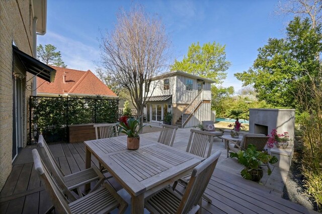 wooden deck featuring an outdoor fireplace, a patio, outdoor dining area, and stairway