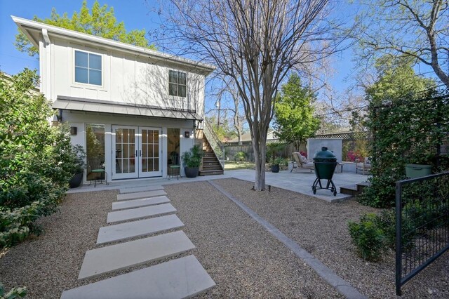 rear view of property featuring french doors, fence, a patio area, stairway, and board and batten siding