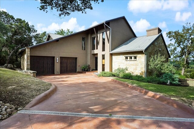 1002 Arroweye Trl, Austin, TX 78733 - view of front of house with stone siding, concrete driveway, an attached garage, a chimney, and metal roof