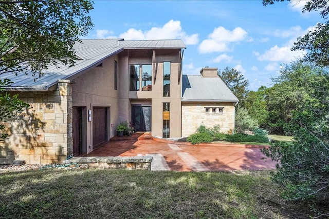 1002 Arroweye Trl, Austin, TX 78733 - rear view of property with stone siding, metal roof, a patio area, stucco siding, and a chimney