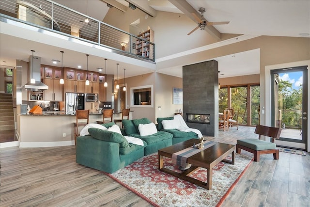 1002 Arroweye Trl, Austin, TX 78733 - living area with light wood-style flooring, beamed ceiling, a tile fireplace, a ceiling fan, and high vaulted ceiling