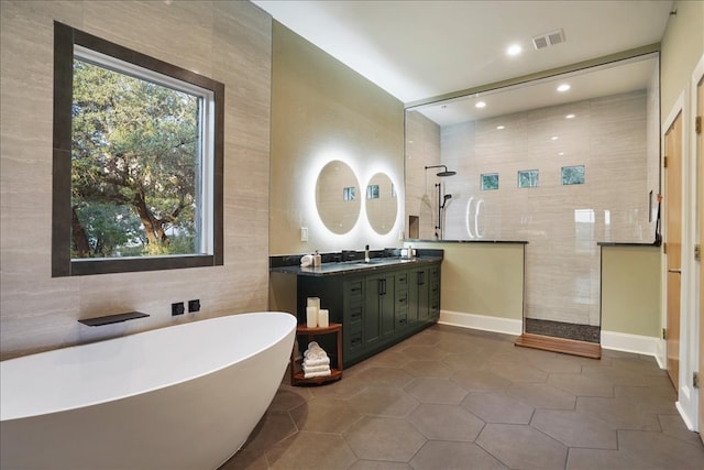 1002 Arroweye Trl, Austin, TX 78733 - full bath with tile walls, walk in shower, a soaking tub, double vanity, and tile patterned floors
