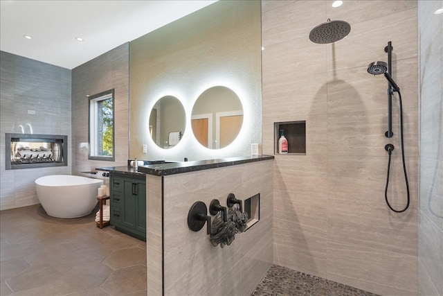 1002 Arroweye Trl, Austin, TX 78733 - full bath featuring a multi sided fireplace, vanity, tile walls, a tile shower, and a soaking tub