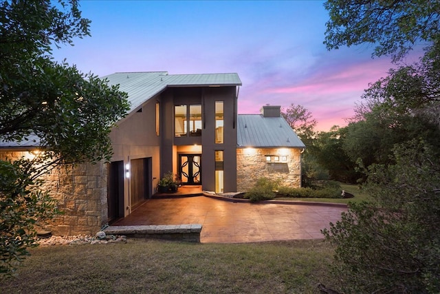 1002 Arroweye Trl, Austin, TX 78733 - view of front facade featuring stone siding, metal roof, a chimney, and a patio