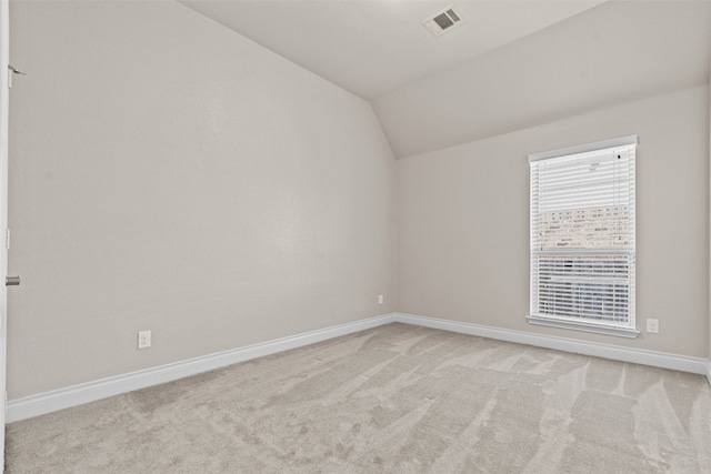 spare room featuring baseboards, visible vents, carpet, and vaulted ceiling