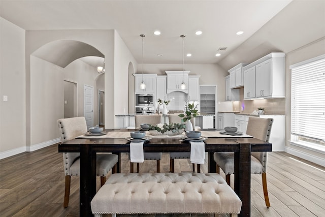 dining area featuring vaulted ceiling, recessed lighting, baseboards, arched walkways, and wood finished floors