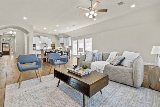 living area with recessed lighting, arched walkways, light wood-style floors, visible vents, and a ceiling fan
