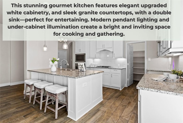 kitchen featuring stainless steel gas stovetop, tasteful backsplash, dark wood-type flooring, light stone counters, and built in microwave