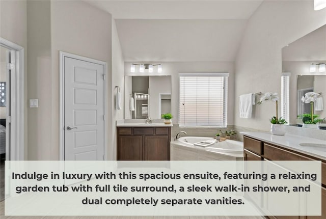 bathroom with a sink, lofted ceiling, a bath, and two vanities