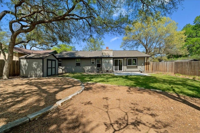 rear view of property with a storage unit, an outdoor structure, a fenced backyard, a patio, and a yard