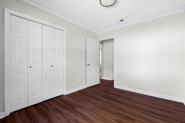 unfurnished bedroom featuring visible vents, crown molding, baseboards, a closet, and dark wood-style floors