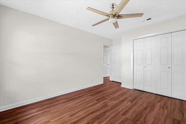 unfurnished bedroom with a textured ceiling, baseboards, a closet, and wood finished floors