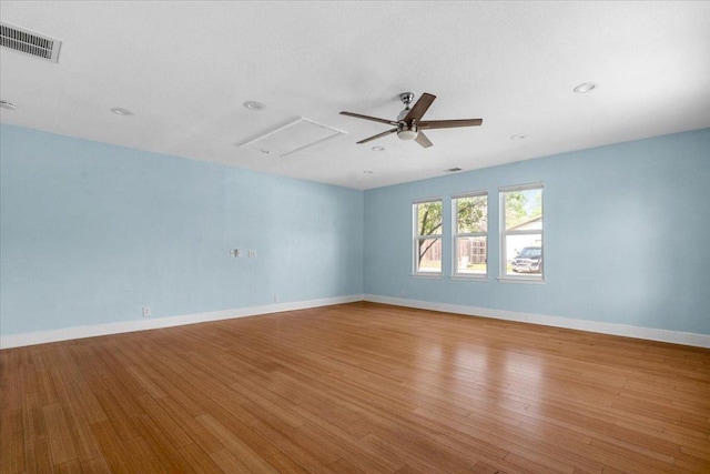 spare room featuring a ceiling fan, baseboards, visible vents, and wood finished floors