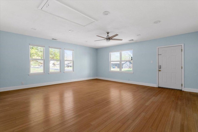 interior space with a ceiling fan, attic access, visible vents, wood finished floors, and baseboards