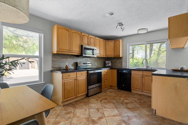 kitchen with backsplash, visible vents, appliances with stainless steel finishes, dark countertops, and a sink