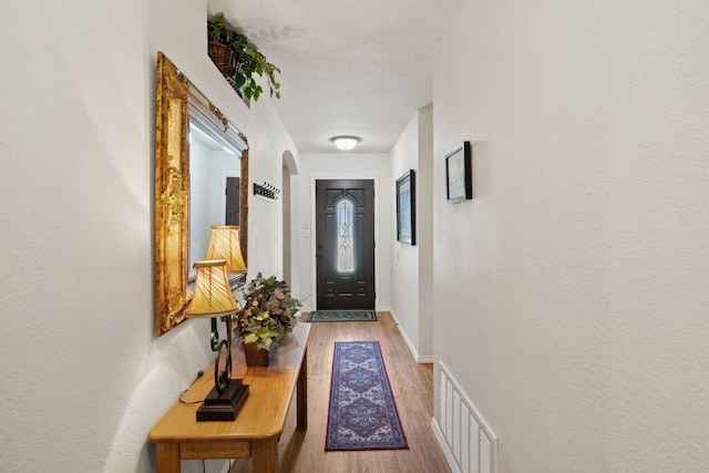3919 Haleys Way, Round Rock, TX 78665 - doorway to outside with arched walkways, wood finished floors, a textured wall, and baseboards