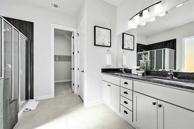 2316 Gold Dust Trl, Leander, TX 78641 - bathroom with a shower stall, double vanity, a walk in closet, and tile patterned floors