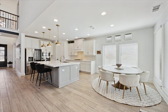 kitchen with stainless steel appliances, visible vents, a sink, and a center island with sink