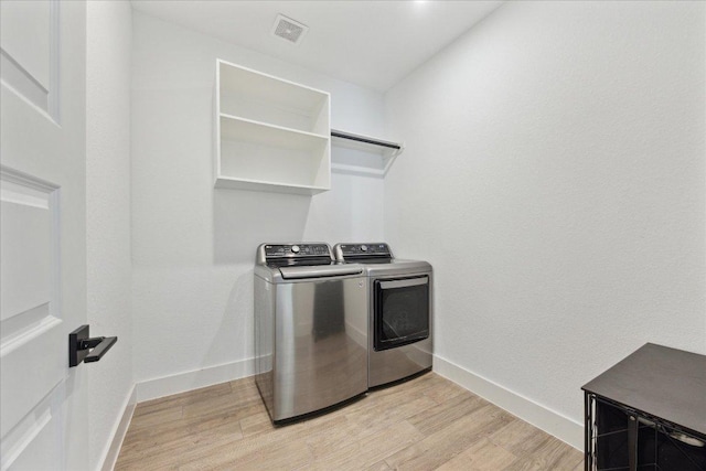 washroom with washing machine and clothes dryer, visible vents, laundry area, and light wood-type flooring