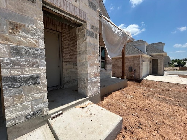 8213 Grenadier Dr, Austin, TX 78738 - doorway to property featuring brick siding, an attached garage, driveway, and a shingled roof
