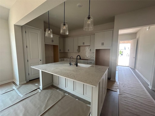 8213 Grenadier Dr, Austin, TX 78738 - kitchen with a large island with sink, baseboards, backsplash, white cabinets, and light stone counters