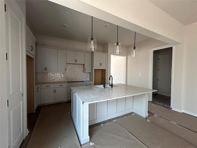 8213 Grenadier Dr, Austin, TX 78738 - kitchen with a sink, tasteful backsplash, black electric cooktop, an island with sink, and light stone countertops