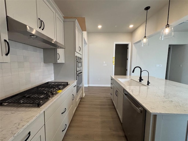 8213 Grenadier Dr, Austin, TX 78738 - kitchen with stainless steel appliances, under cabinet range hood, dark wood-style floors, a center island with sink, and tasteful backsplash