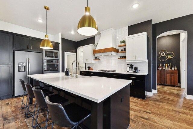 308 Somerset Hills Dr, Georgetown, TX 78633 - kitchen featuring stainless steel appliances, custom exhaust hood, arched walkways, open shelves, and light countertops