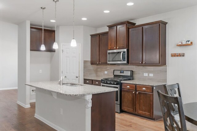 13601 Larrys Ln, Manchaca, TX 78652 - kitchen featuring a sink, tasteful backsplash, light wood-style floors, and appliances with stainless steel finishes