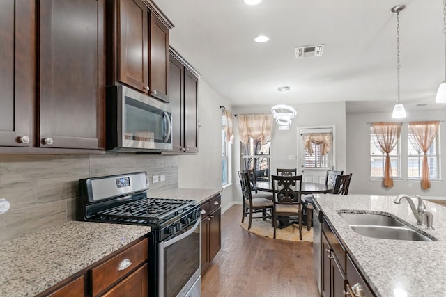 13601 Larrys Ln, Manchaca, TX 78652 - kitchen with appliances with stainless steel finishes, a sink, wood finished floors, dark brown cabinets, and backsplash