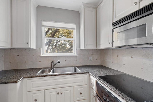 2610 Allston Ln, Austin, TX 78746 - kitchen with stainless steel microwave, black electric stovetop, white cabinets, tasteful backsplash, and dark countertops