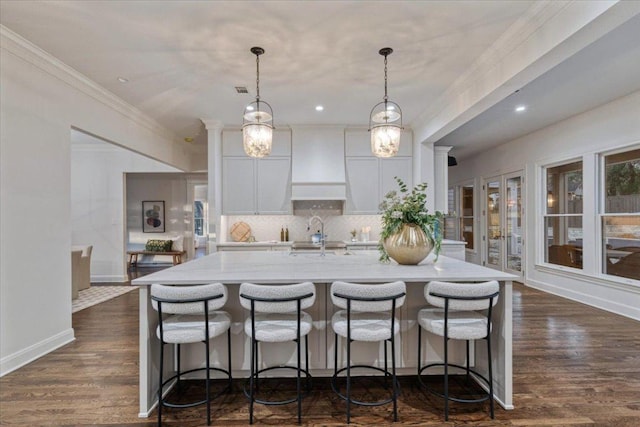 2610 Allston Ln, Austin, TX 78746 - kitchen featuring custom exhaust hood, a spacious island, backsplash, white cabinetry, and decorative light fixtures