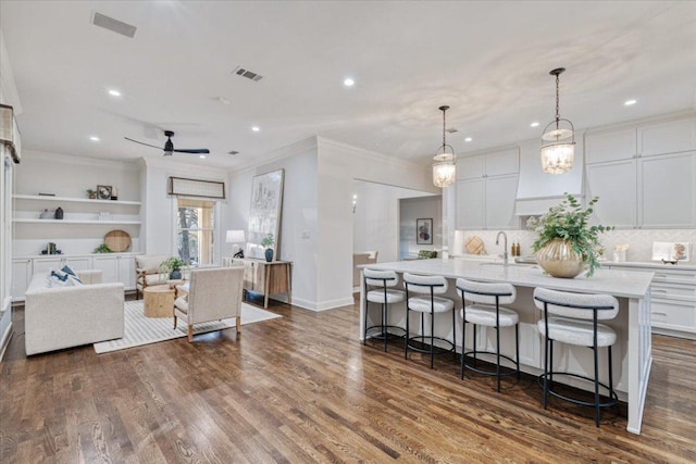 2610 Allston Ln, Austin, TX 78746 - kitchen featuring light countertops, white cabinets, a kitchen island with sink, a kitchen bar, and recessed lighting