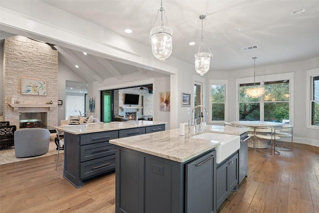 4229 Verano Dr, Austin, TX 78735 - kitchen with a fireplace, a kitchen island with sink, gray cabinets, open floor plan, and recessed lighting