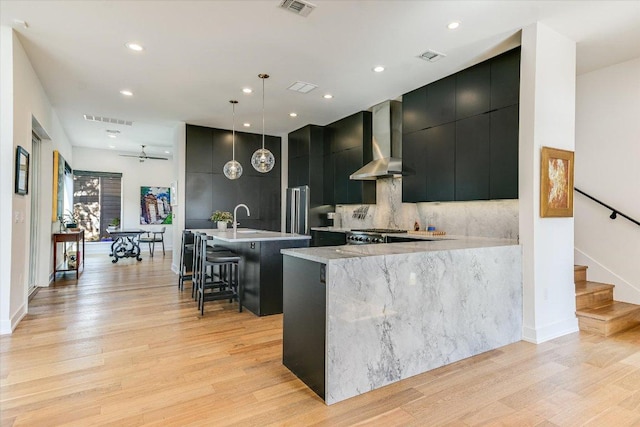 2010 Goodrich Ave Unit 8A, Austin, TX 78704 - kitchen featuring wall chimney range hood, dark cabinets, modern cabinets, light wood-type flooring, and recessed lighting