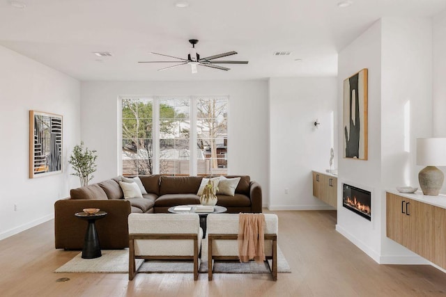 3607 Garden Villa Ln, Austin, TX 78704 - living area with ceiling fan, light wood-style floors, a glass covered fireplace, and baseboards