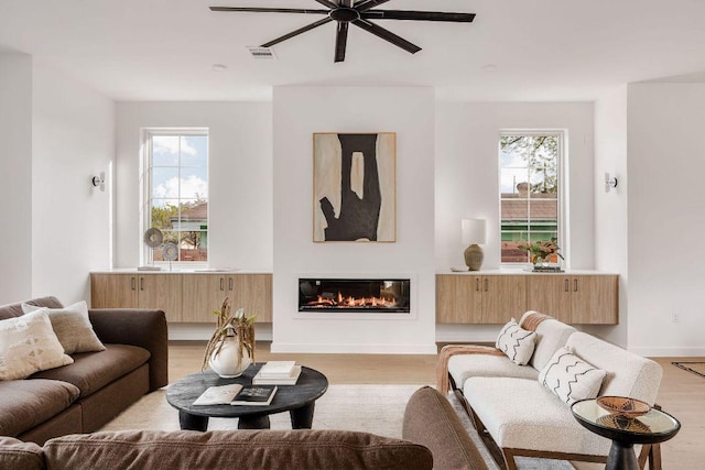 3607 Garden Villa Ln, Austin, TX 78704 - living room featuring a ceiling fan, light wood-style floors, healthy amount of natural light, and a glass covered fireplace