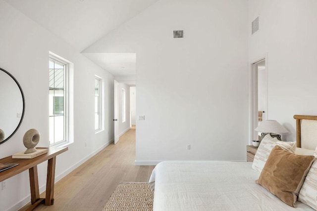 3607 Garden Villa Ln, Austin, TX 78704 - bedroom featuring light wood finished floors, multiple windows, a towering ceiling, and baseboards