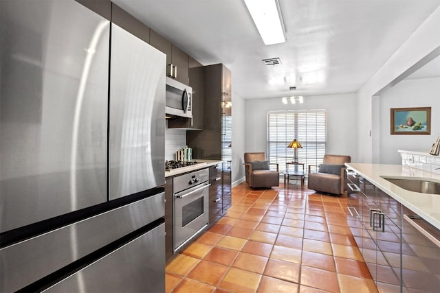 1908 Running Brook Dr, Austin, TX 78723 - kitchen featuring appliances with stainless steel finishes, a sink, light countertops, light tile patterned floors, and backsplash
