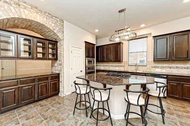 412 Madisons Way, Cedar Park, TX 78613 - kitchen featuring appliances with stainless steel finishes, a kitchen breakfast bar, dark stone countertops, dark brown cabinets, and backsplash