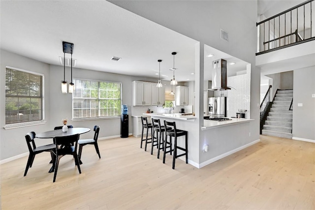 2004 Wood Glen Dr, Round Rock, TX 78681 - kitchen with wall chimney exhaust hood, stainless steel appliances, light wood-style floors, a kitchen breakfast bar, and recessed lighting
