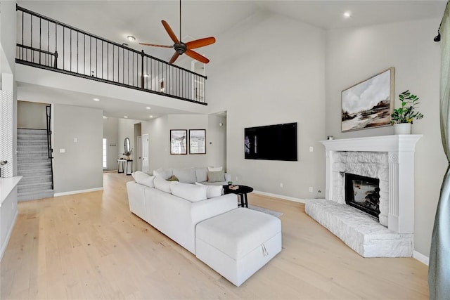 2004 Wood Glen Dr, Round Rock, TX 78681 - living area featuring ceiling fan, light wood-type flooring, stairs, a fireplace with raised hearth, and a towering ceiling