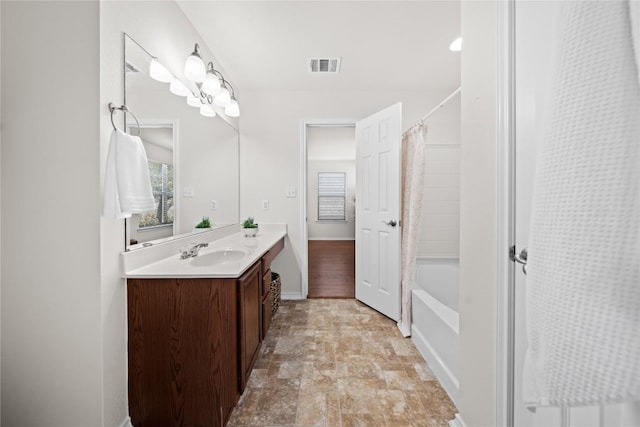 full bath featuring vanity, baseboards, visible vents, shower / bath combo with shower curtain, and stone finish flooring