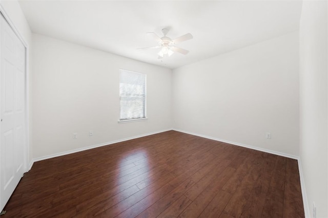 unfurnished room featuring baseboards, dark wood-style floors, and a ceiling fan