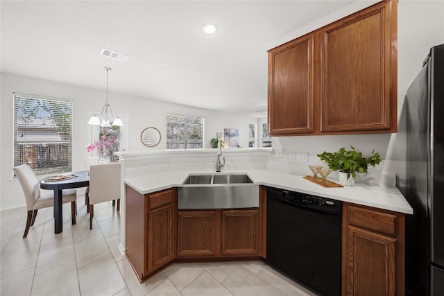 kitchen featuring light countertops, a sink, pendant lighting, a peninsula, and black appliances