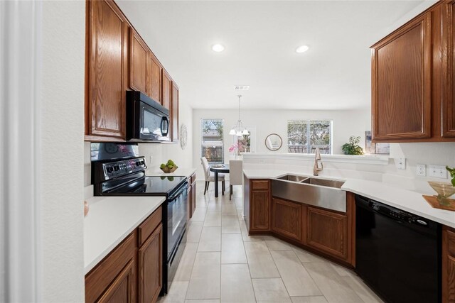 kitchen with light countertops, a sink, a peninsula, and black appliances
