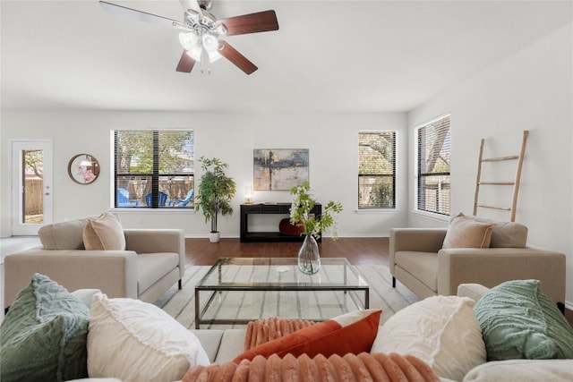 living area with a wealth of natural light, wood finished floors, baseboards, and a ceiling fan