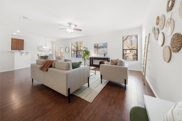 living area with dark wood finished floors, a wealth of natural light, visible vents, and a ceiling fan
