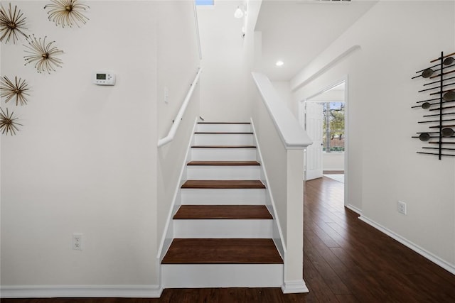 staircase with baseboards, visible vents, and wood finished floors