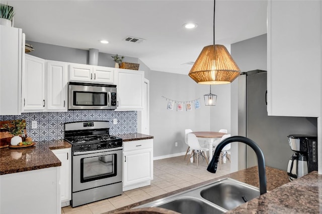 704 Firethorn Ln, Round Rock, TX 78664 - kitchen featuring stainless steel appliances, light tile patterned floors, decorative backsplash, white cabinetry, and pendant lighting